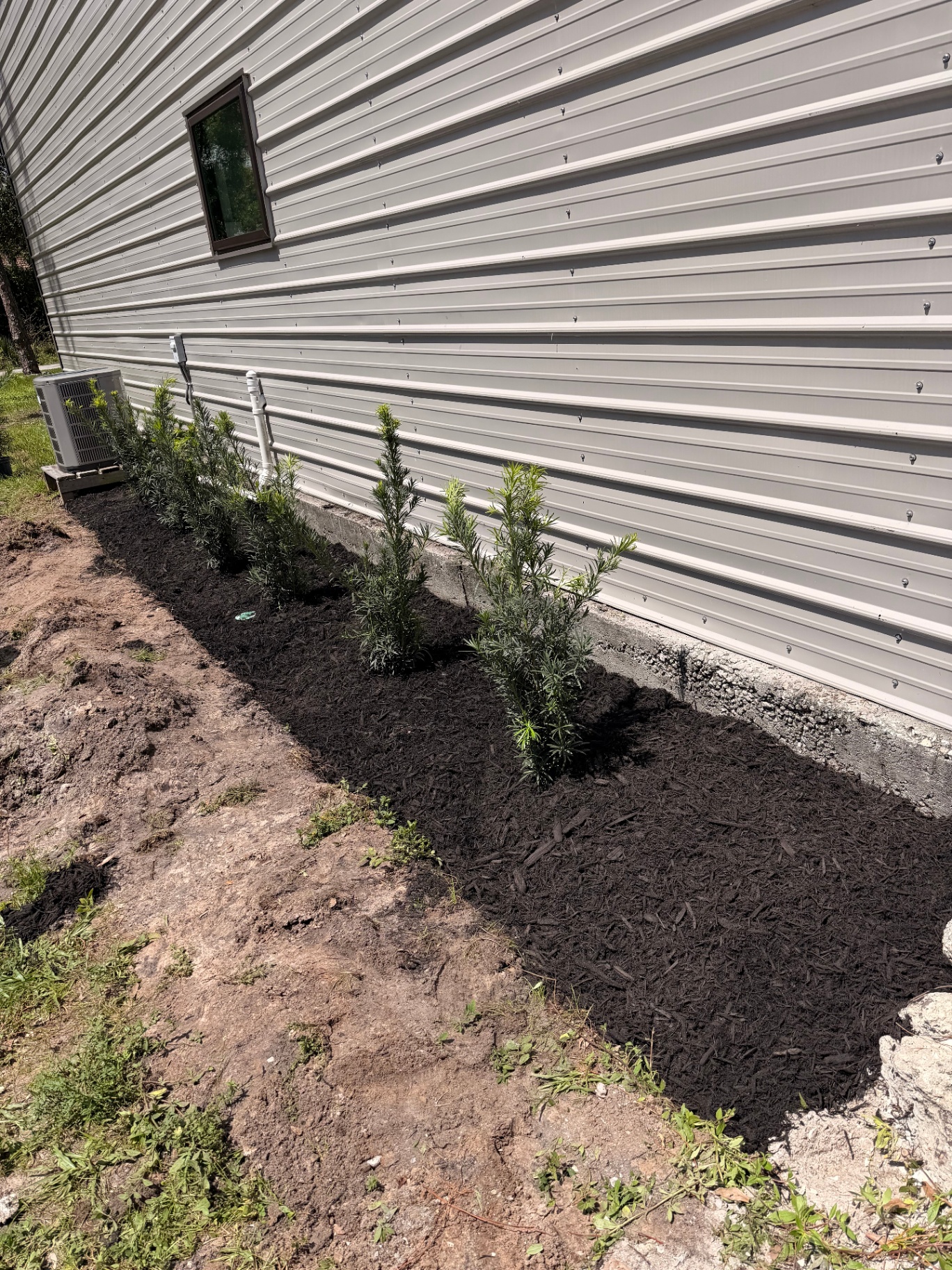 Freshly mulched landscape bed installed along the side of a home
